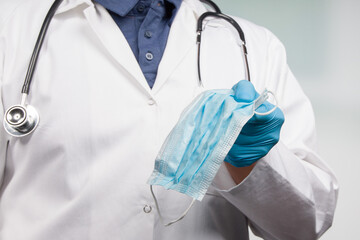 close up of doctor's hand in medical gloves presenting a medical face mask