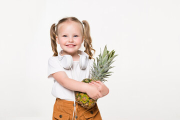 Smiling little girl holding pineapple on white background