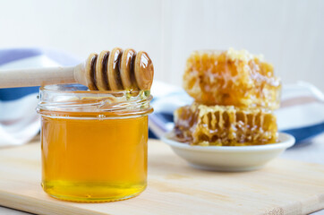 natural flower honey in glass jar with dipper and honeycombs. soft focus. space for text