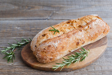 Homemade fresh crispy italian ciabatta with rosemary sprigs on a wooden board. Copy space