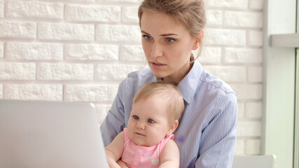 Concentrated woman with baby working on laptop. Business woman working