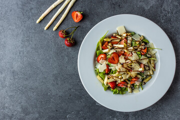 Healthy salad with strawberry, white asparagus, arugula, parmesan cheese. Top view. Copy space