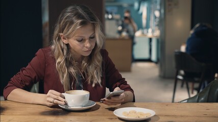 Attractive woman in cafe browsing the Internet using smart phone and waiting some meeting with friend.. High quality photo. 