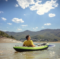 Young man relaxing in a canoe on a lake by the mountains