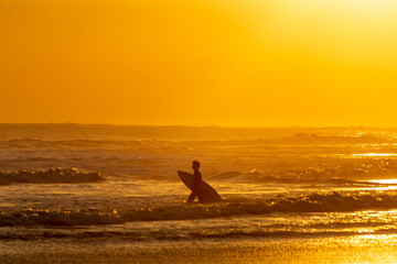 Tropical sunsets in Bali with surfer