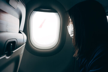 dult asian woman on airplane seat near window on day light wear face mask for corona virus
