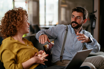 Colleagues sitting and talkig in office. Businesswoman and businessman discussing work in office..