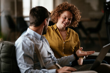 Colleagues sitting and talkig in office. Businesswoman and businessman discussing work in office..