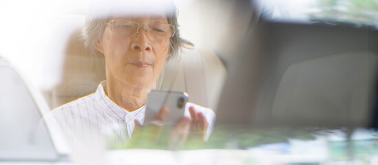Asian elderly woman use digital tablet in the car or taxi for social media and communication