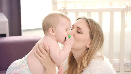 Happy mother kissing baby. Young mother cuddling baby