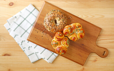Top view of assorted breads on the wooden breadboard with kitchen cloth	