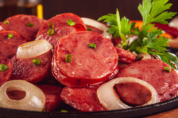 Sliced smoked fried calabrese sausage with onion - Brazilian appetizer close-up