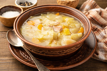 Homemade cabbage soup in ceramic bowl on rustic wooden background