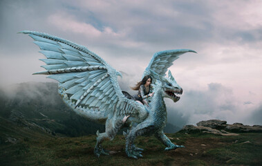 A young woman sits astride a dragon. Fantasy photography. A huge creature with spikes and wings...