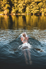 Woman goes into the river for a swim. Early morning light