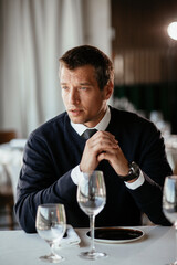 Handsome businessman dressed in the suit drinking wine. Businessman enjoying in the restaurant..