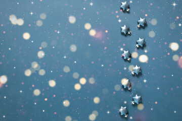 Christmas decorative stars on a blue background with bokeh lights. Holiday greeting card.