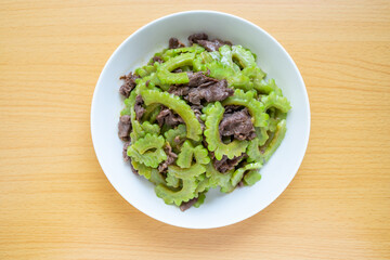 Stir-fried beef with bitter gourd on a dish of home cooking on wooden table