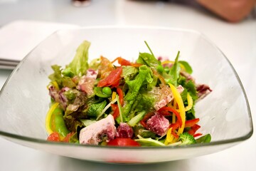 Salad with bacon on transparent dish.