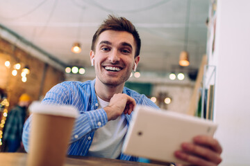 Smiling guy with coffee sitting at table in cafeteria