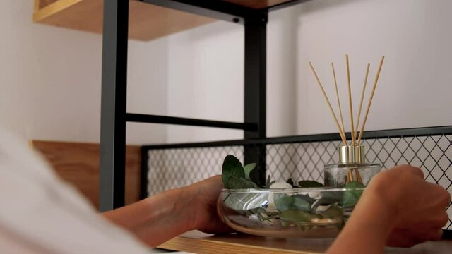 home improvement, decoration and people concept - woman placing aroma reed diffuser to shelf