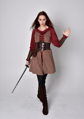 Full length portrait of girl wearing medieval costume. Standing pose holding a sword,  isolated...