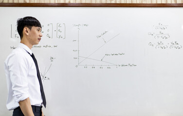 Asian teacher is teaching and writing on a whiteboard.