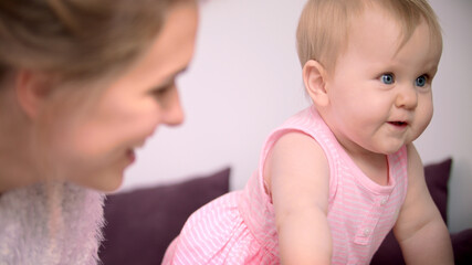 Child learning to walk with mother. Beautiful infant girl crawling at home