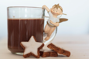 Christmas angel on cup of hot chocolate and delicious homemade cookies