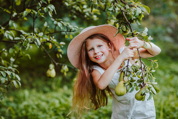 Pretty girl posing with the branch of green pears in the garden.