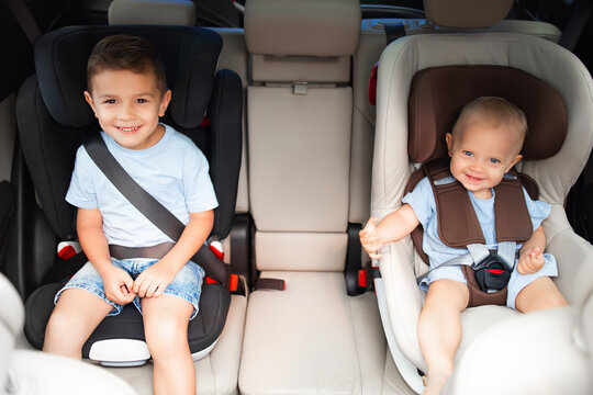 Kids, little girl with her brother sitting together in car seat locked with safety belts