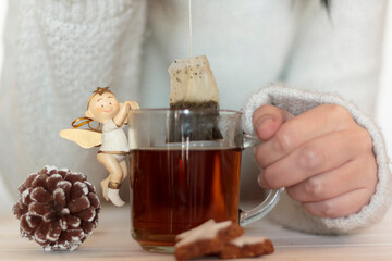 Woman hands dipping tea bag in hot water with winter decoration