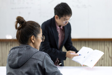 Asian teacher is teaching students in the classroom.