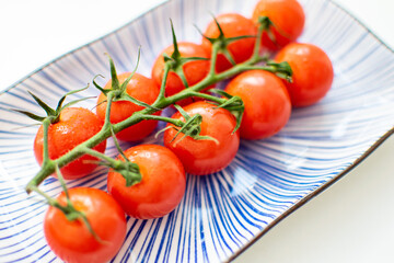 a vine of cherry tomatoes presented on a blue ceramic plate