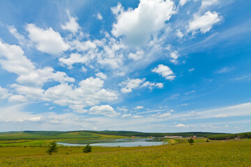 lake and green grass under the blue sky and white clouds