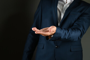 The man in the suit holds out his palm.