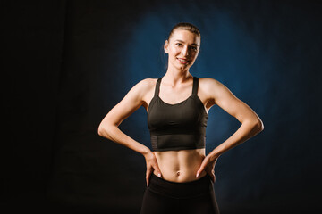 Fototapeta na wymiar Slim sport woman doing exercises on the black studio background