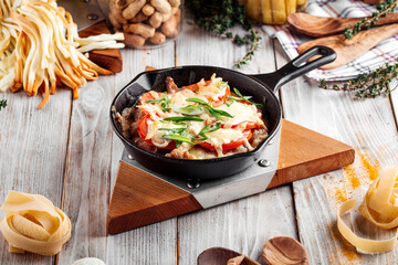 Chicken with tomatoes and cheese in cast iron pan