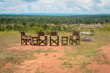 Empty chairs and table with view on the landscape of an African national park during a safari trip
