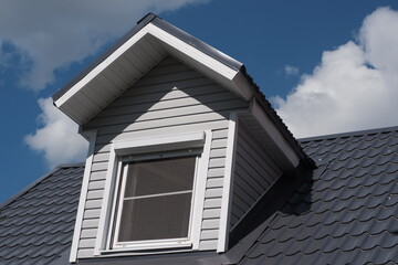 Gray roof of the house against the blue sky. The roof is made of metal.