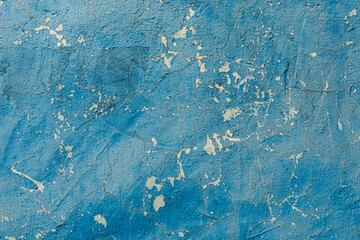 Old cracked blue wall as background. In some places, paint has fallen off and plaster is visible