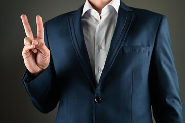 Man in suit shows peace symbol with his hand