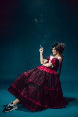 Cigarette smoking. Young woman as Anna Karenina isolated on dark blue background. Retro style,...