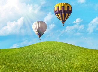 Dream world. Hot air balloons in sky with clouds over green meadow