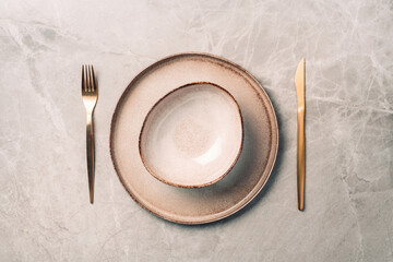 Stoneware plate setting with knife and fork on marble background. Top view. Copy space. Flat lay....