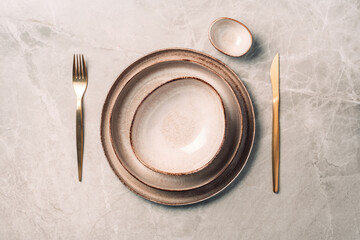 Stoneware plate setting with knife and fork on marble background. Top view. Copy space. Flat lay. Serving a festive table concept