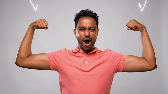 power, strength, sport and success concept - happy young indian man showing biceps and celebrating success over grey background with animated glowing lines