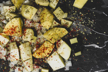 vegetable eggplant slices, onion slices and potato slices with spices on the black table
