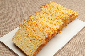 Homemade Brazilian corn bread sliced on a cutting board. Isolated on jute background. Close-up