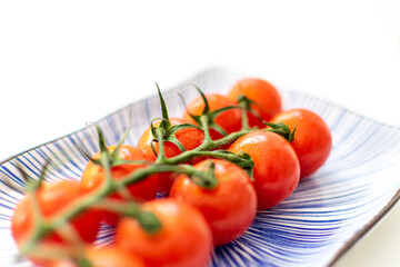 a abstract image of a vine of cherry tomatoes on a ceramic plate with blue pattern 